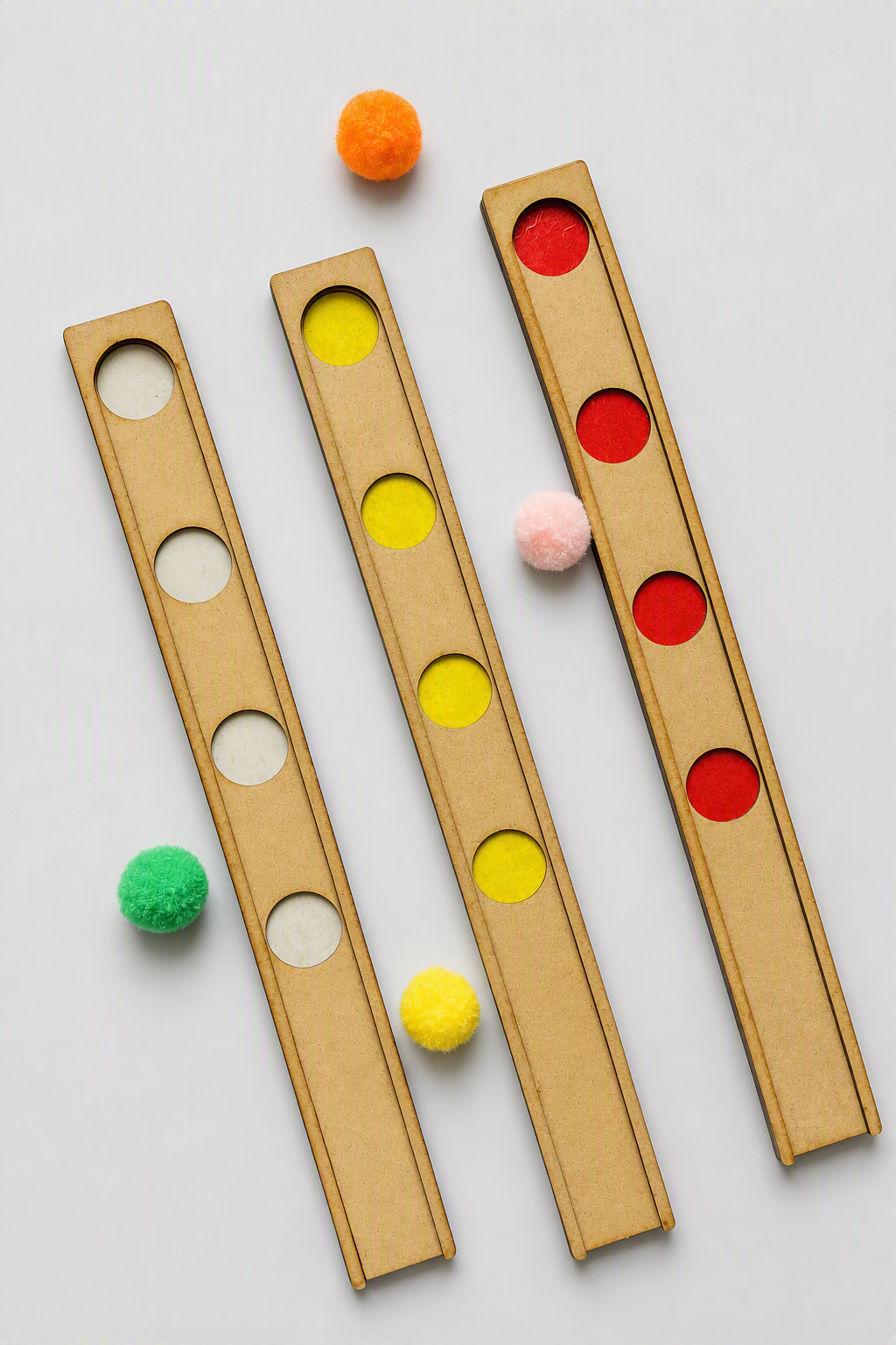 Three wooden boards with circular slots, shown on a light gray background with colorful pom-poms placed in or near the slots.