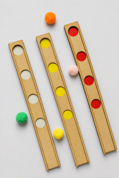 Three wooden boards with circular slots, shown on a light gray background with colorful pom-poms placed in or near the slots.